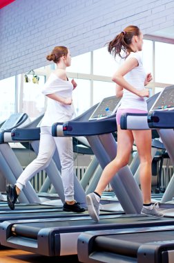 makine üzerinde çalışan iki genç sportif kadın