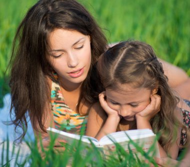 mutlu kız yeşil çimenlerin üzerinde kitap okuma