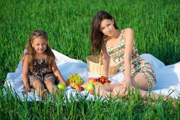 Happy girls on green grass with fruits — Stock Photo, Image