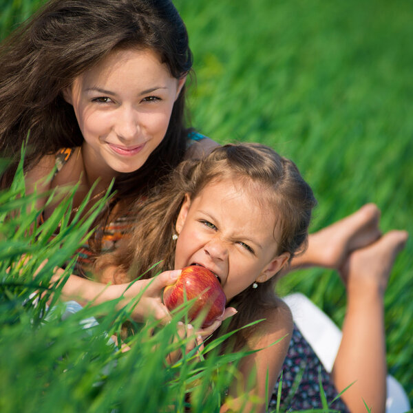 Happy girls on green grass with apple