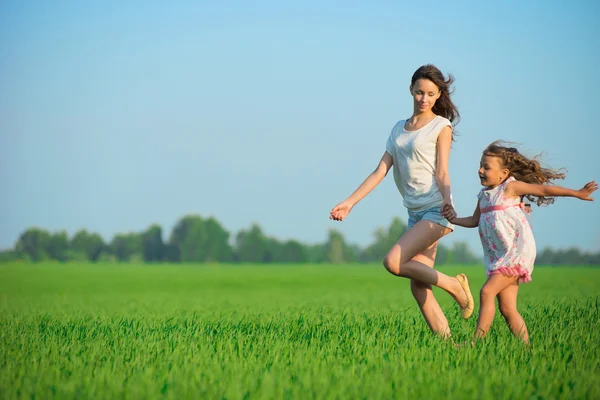 Jovens meninas felizes correndo no campo de trigo verde — Fotografia de Stock