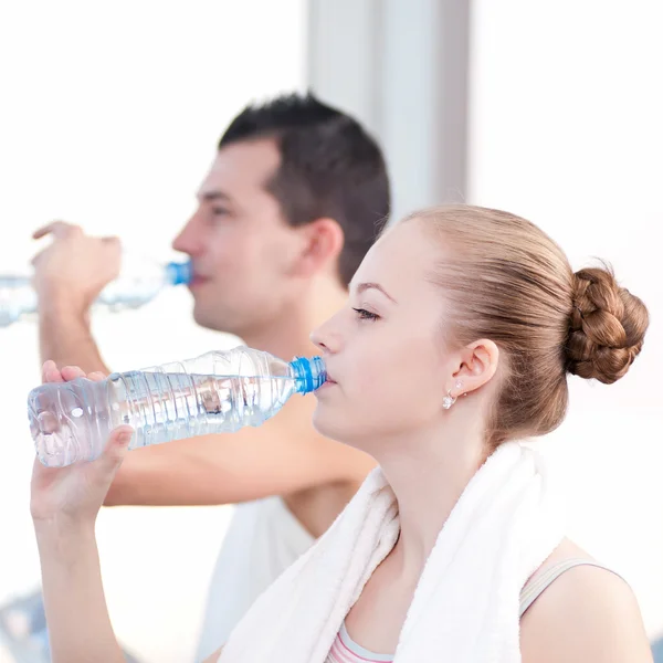 Mann und Frau trinken nach Sport in Turnhalle Wasser — Stockfoto