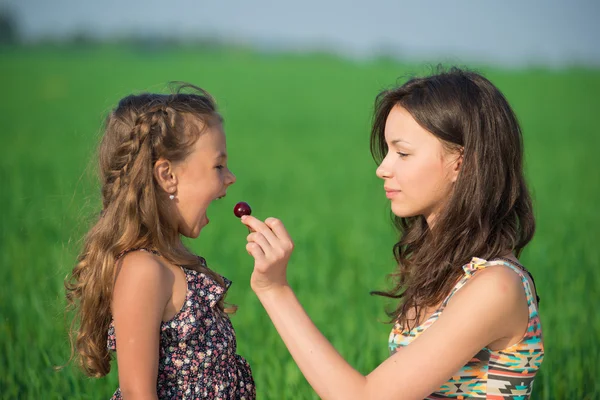 Ragazze felici mangiare frutta su erba verde — Foto Stock