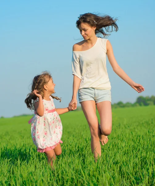 Young happy girls running at green wheat field — Stock Photo, Image