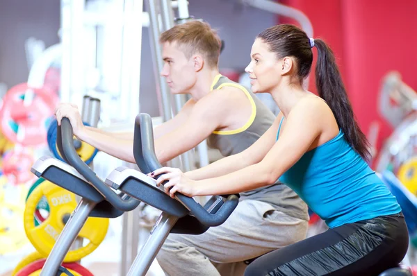 Les gens dans la salle de gym faisant de la formation cardio-cyclisme — Photo