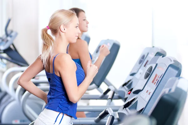 Twee jonge vrouwen draaien op machine in de sportschool — Stockfoto