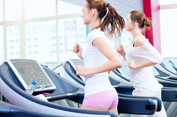 Two young sporty women run on machine — Stock Photo, Image