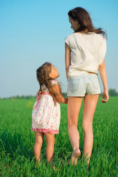 Young happy girls walking at green wheat field — Stock Photo, Image