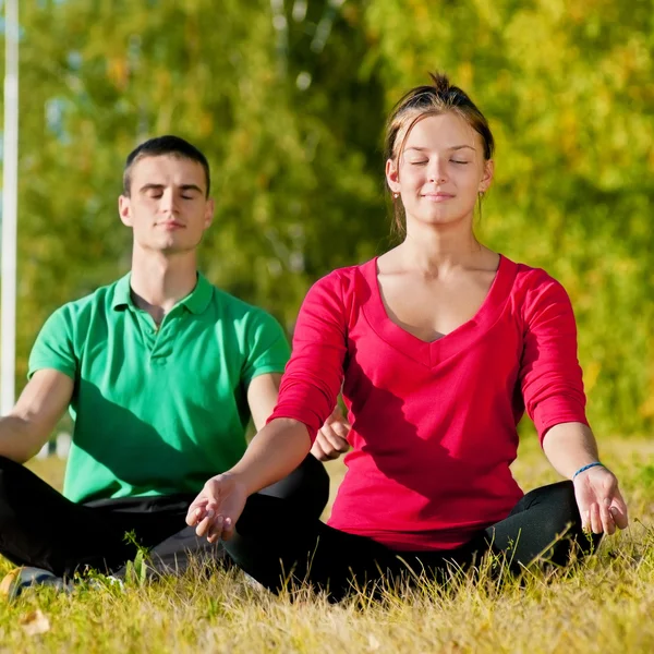 Homem e mulher fazendo ioga no parque — Fotografia de Stock