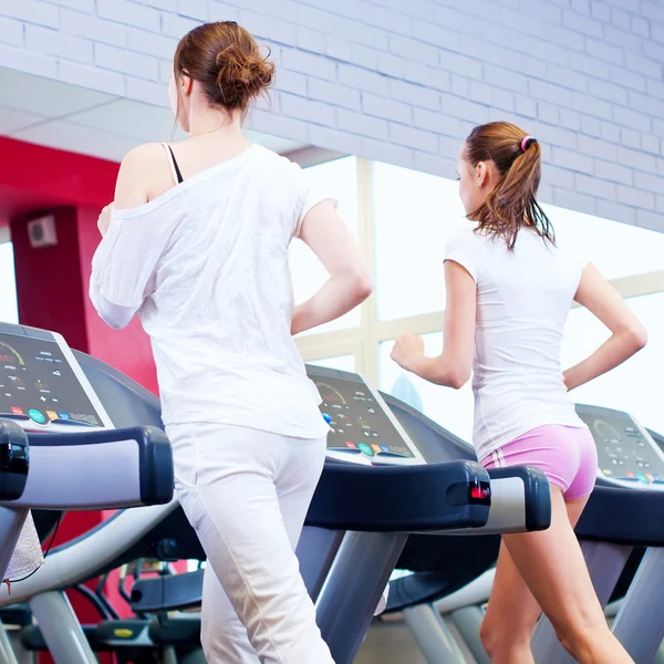 Two young sporty women run on machine — Stock Photo, Image