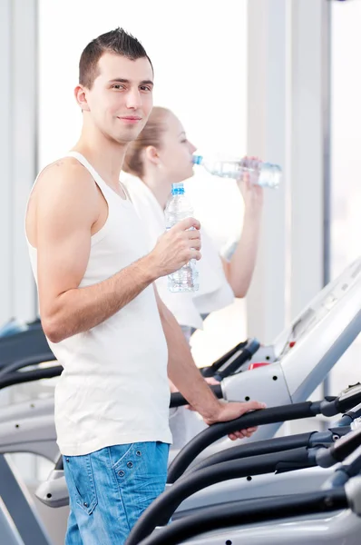 Hombre y mujer bebiendo agua después de los deportes en el gimnasio — Foto de Stock