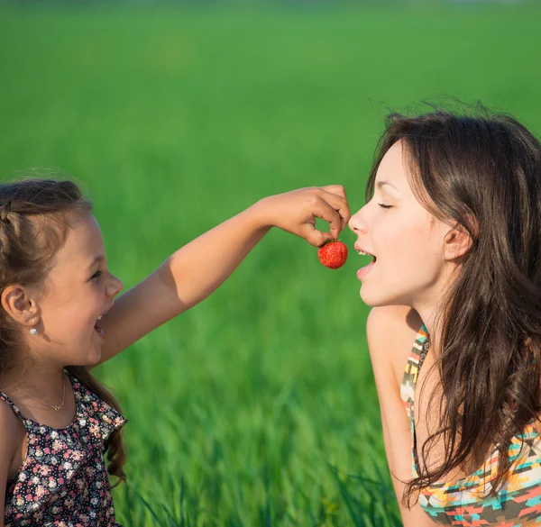 Glückliche Mädchen essen Früchte auf grünem Gras — Stockfoto