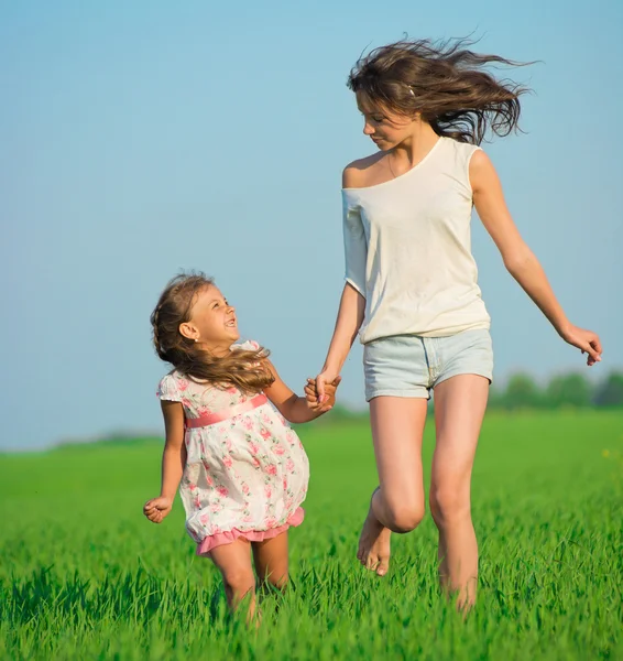 Young happy girls running at green wheat field — Stock Photo, Image