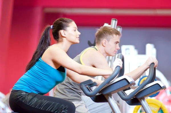 Gente en el gimnasio haciendo entrenamiento de ciclismo cardiovascular —  Fotos de Stock