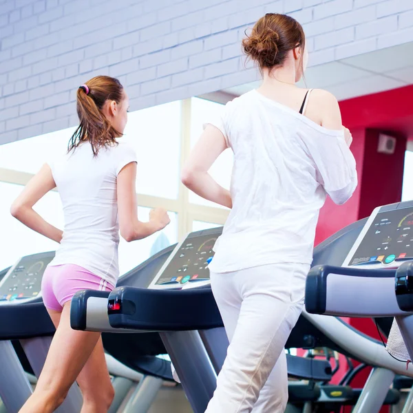 makine üzerinde çalışan iki genç sportif kadın