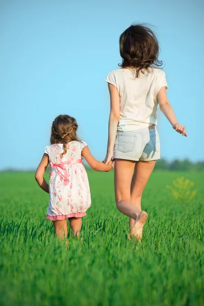 Jóvenes chicas felices corriendo en el campo de trigo verde — Foto de Stock