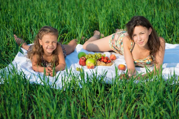 Happy girls on green grass with fruits — Stock Photo, Image