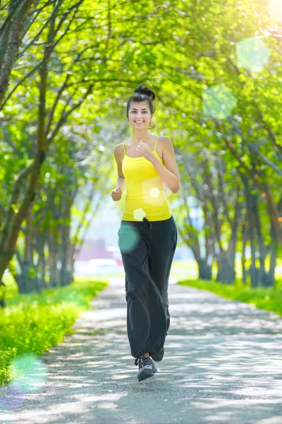 Бегунья - женщина, бегущая на открытом воздухе в зеленом парке — стоковое фото