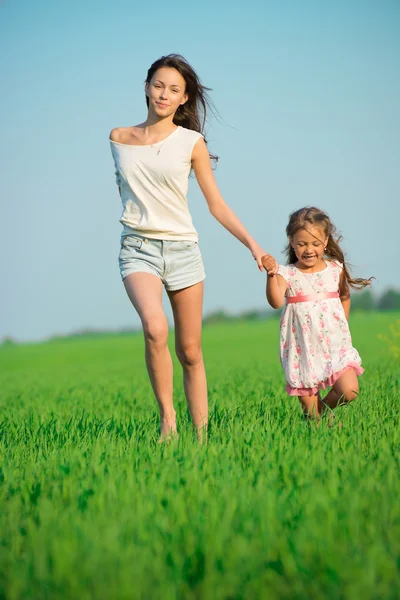 Gelukkig meisjes lopen bij groene tarweveld — Stockfoto