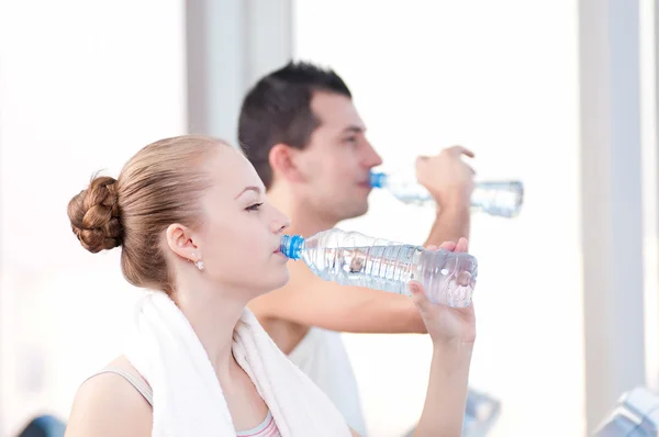 Mężczyzna i kobieta wody pitnej po sportowych w sali gimnastycznej — Zdjęcie stockowe