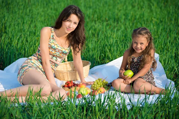 Happy girls on green grass with fruits — Stock Photo, Image