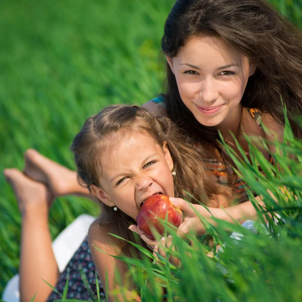Szczęśliwy dziewcząt na zielonej trawie z jabłkiem — Zdjęcie stockowe