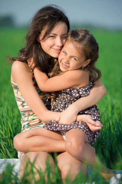 Happy girls on green grass embrace — Stock Photo, Image