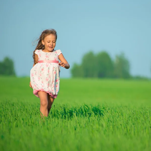 Joven chica feliz corriendo en el campo de trigo verde — Foto de Stock