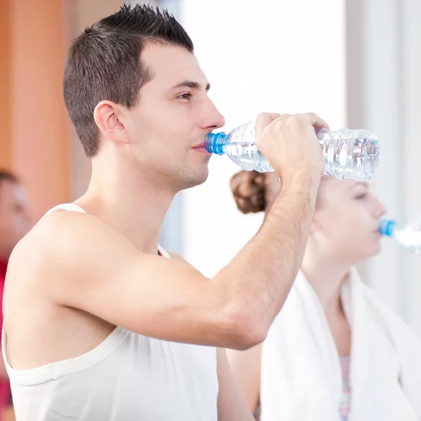 Чоловік і жінка п'ють воду після спорту в спортзалі — стокове фото