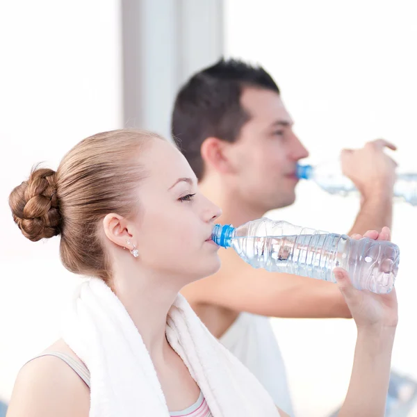 Mann und Frau trinken nach Sport in Turnhalle Wasser — Stockfoto