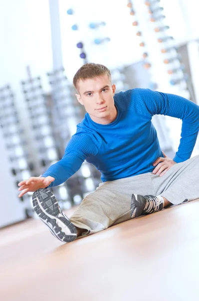 Hombre haciendo ejercicios de estiramiento en el gimnasio — Foto de Stock