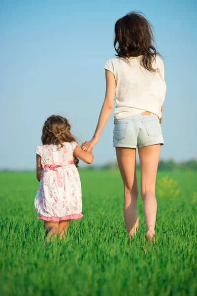 Gelukkig meisjes lopen bij groene tarweveld — Stockfoto