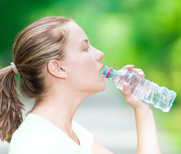 Woman drinking cold mineral water from a bottle after fitness ex — Stock Photo, Image