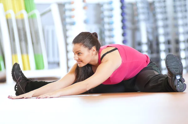 Vrouw doen uitrekkende oefeningen in de sportschool — Stockfoto