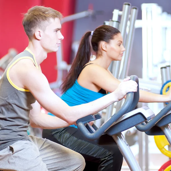 Gente en el gimnasio haciendo entrenamiento de ciclismo cardiovascular —  Fotos de Stock