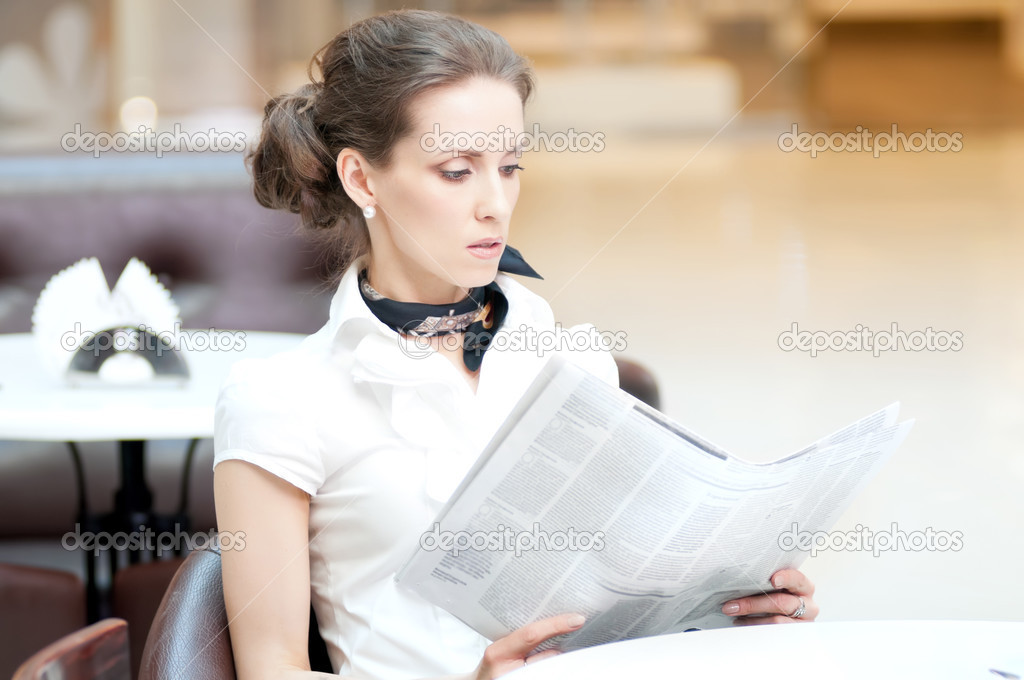 Serious business woman reading newspaper
