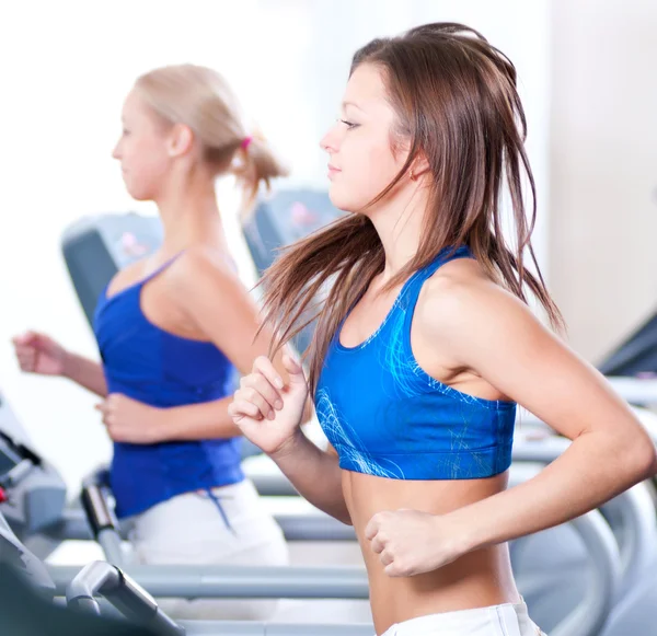 Two young women run on machine — Stock Photo, Image