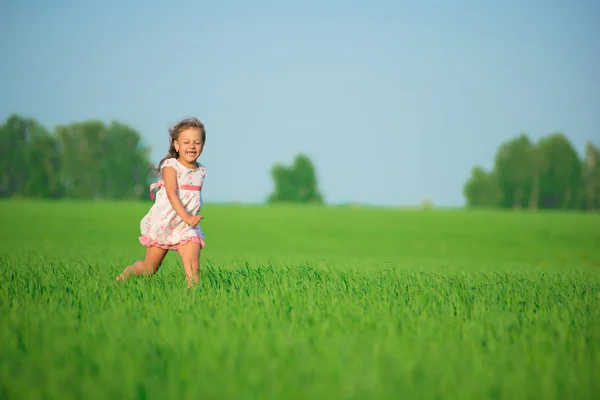 Joven chica feliz corriendo en el campo de trigo verde — Foto de Stock