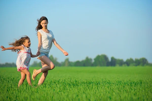 Young happy girls running at green wheat field — Stock Photo, Image