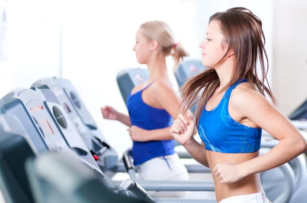 Two young women run on machine — Stock Photo, Image