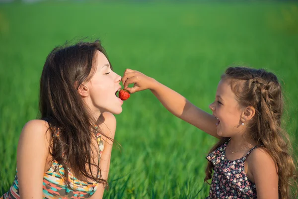 Ragazze felici che mangiano fragole sull'erba — Foto Stock