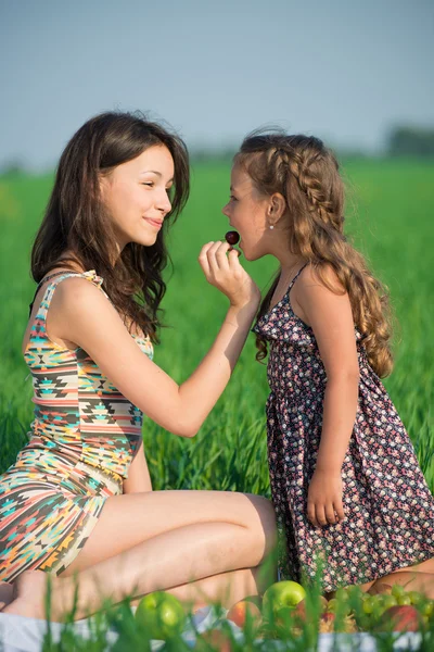 Gelukkig meisjes cherry fruit eten op groen gras — Stockfoto