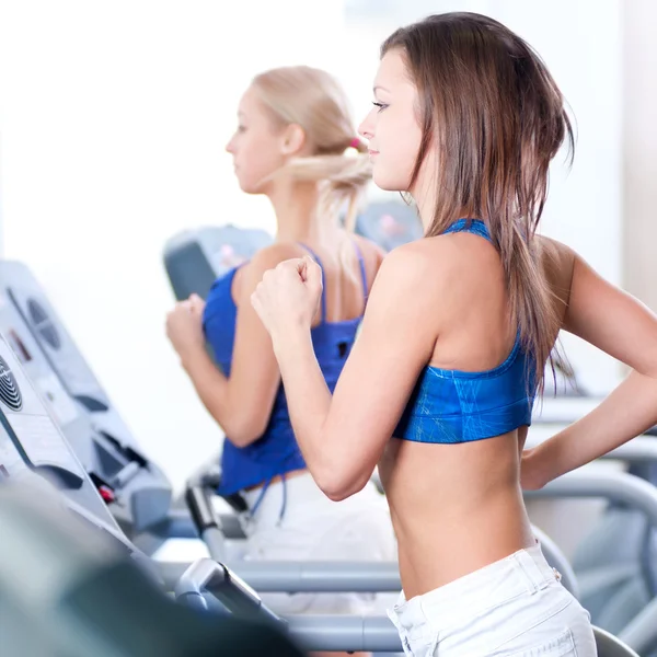 Two young women run on machine — Stock Photo, Image