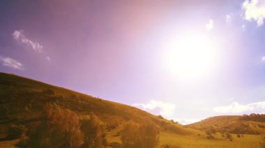 Yazın 4K UHD dağ çayırı zaman dilimi. Bulutlar, ağaçlar, yeşil çimenler ve güneş ışınları hareketi.