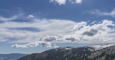 Dağların arkasındaki bulutların zaman çizelgesi. Kar, kayalar, uçurumlar ve derin mavi gökyüzü. Yüksek irtifa.