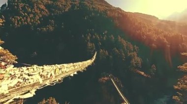 Khumbu vadisindeki en büyük asma köprü renkli Tibet dua bayraklarıyla. Vahşi Himalayalar yüksek irtifa doğa ve dağ vadisi. Ağaçlarla kaplı kayalık yamaçlar. Everest Zirvesi 'nin ana kampı..