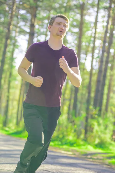 Чоловік біжить у парку міста в прекрасний літній день. Спортивна фітнес-модель кавказької етнічної підготовки на відкритому повітрі . — стокове фото