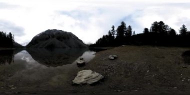 Dağ Gölü 'nün kış zamanı 360 Vr. Vahşi doğa ve dağ vadisi. Çam ağaçlarından yeşil orman ve gökyüzünde hızlı bulutlar.