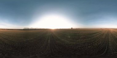 360 hava manzaralı. Güneşli bir sonbahar akşamında sonsuz yeşil tarlaları olan yaz manzarasının üzerinde alçak uçuş. Ufuktaki güneş ışınları. Hızlı yatay hareket. Sabitlendi ve yamandı.