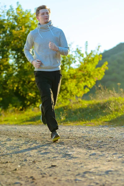 Homme jogging dans la nature rurale lors d'une belle journée d'été. Sport fitness modèle caucasien ethnicité entraînement de plein air. — Photo